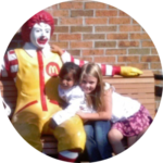 Children smiling with Ronald McDonald statue at community event