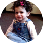 oddler smiling in overalls supported by nonprofit